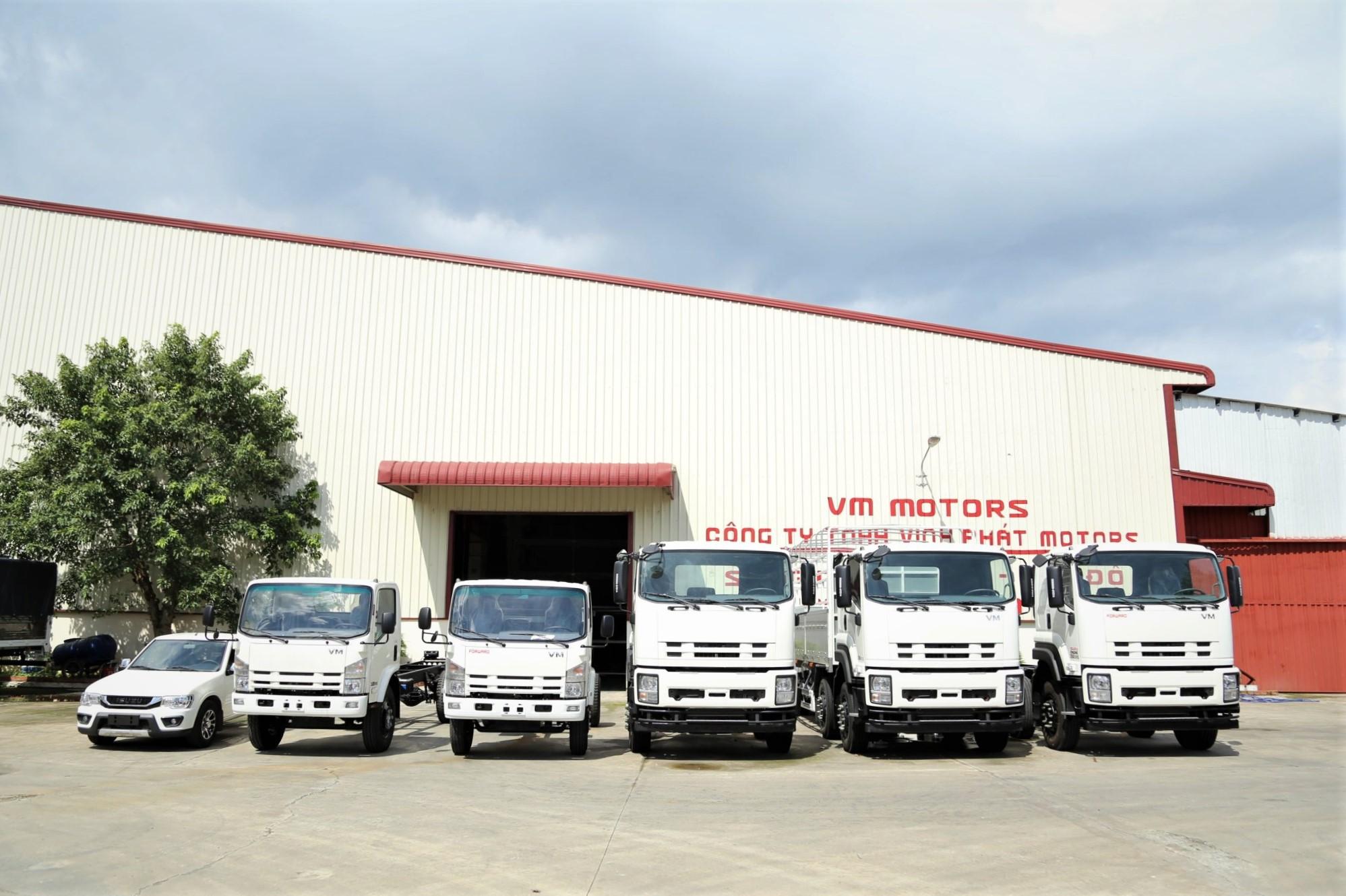 Nhà xưởng VM Motors / Vĩnh Phát Motors cửa đỏ, xe tải trắng đỗ trước; biển hiệu trên mái.