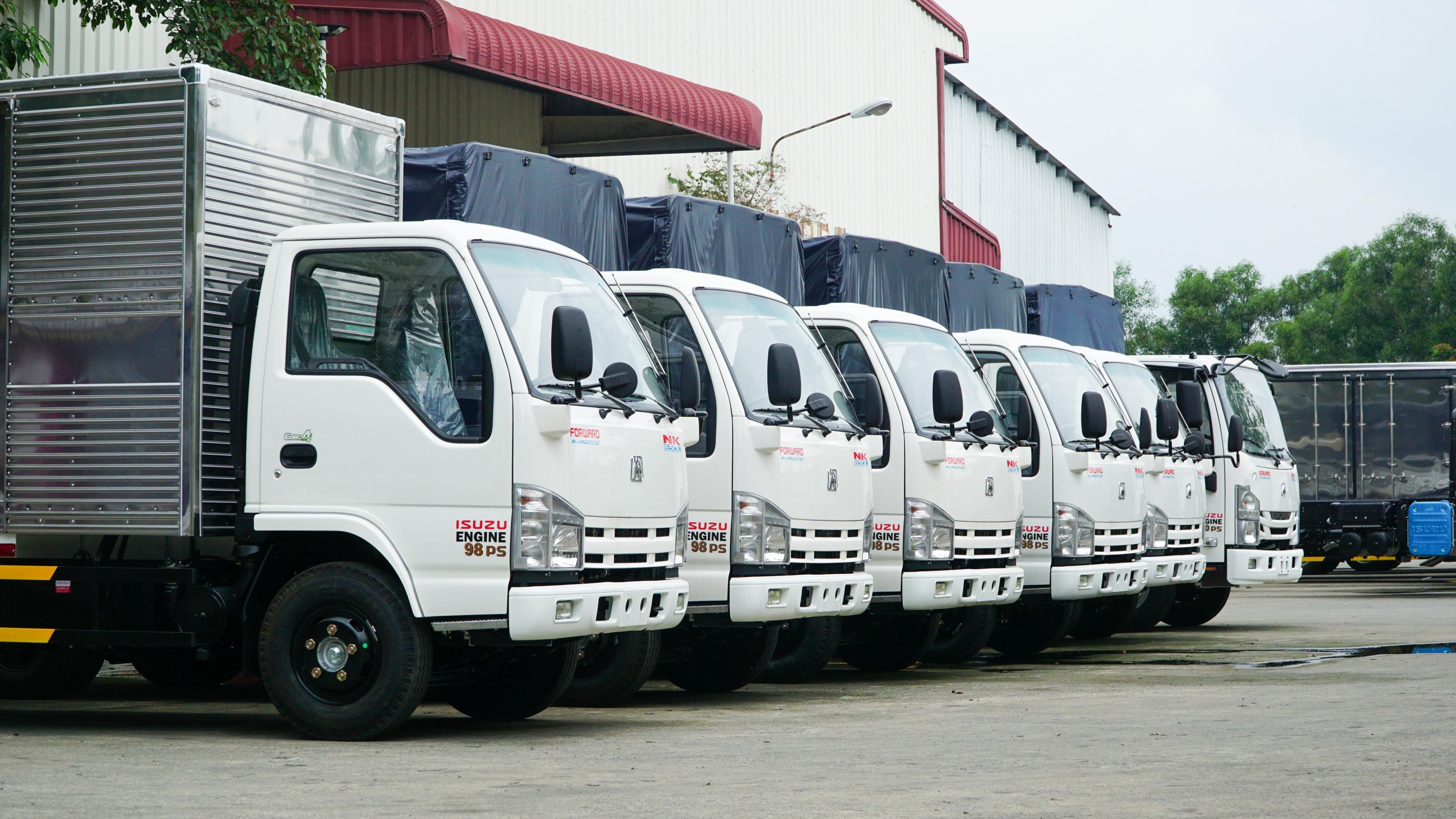 Hai xe tải nhẹ cabin trắng VM TRUCK NK Series, một thùng kín và một thùng lửng, đỗ trên đường.